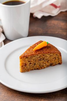 Delicious carrot cake with coffee next to it on wooden table