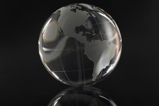 Glass transparent globe on a black background, reflection, close-up. The concept of a world in darkness, cleansing