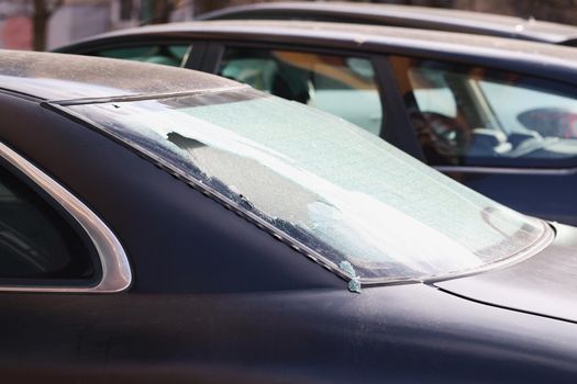 Broken rear window of a car on the street, close-up. Criminal district of the city, vandalism and theft