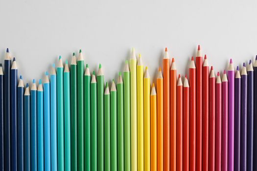 Colored pencils vertically in a row in a wave, close-up. Color palette, design element, wallpaper, creative hobby
