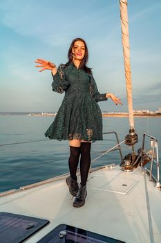 Woman standing on the nose of the yacht at a sunny summer day, breeze developing hair, beautiful sea on background.