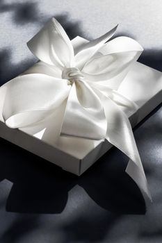 Anniversary celebration, shop sale promotion and luxe surprise concept - Luxury holiday white gift box with silk ribbon and bow on black background, luxe wedding or birthday present