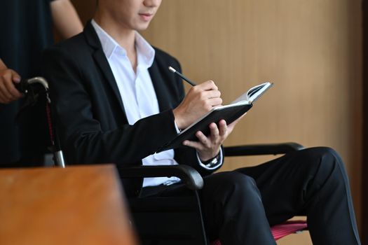 Businessman with disability in wheelchair working in office.