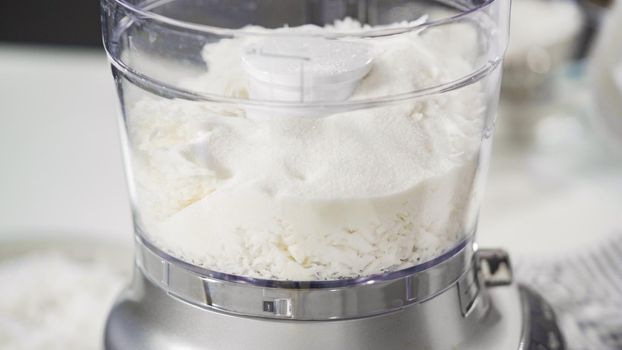 Mixing ingredients in a food processor to prepare homemade coconut cookies.