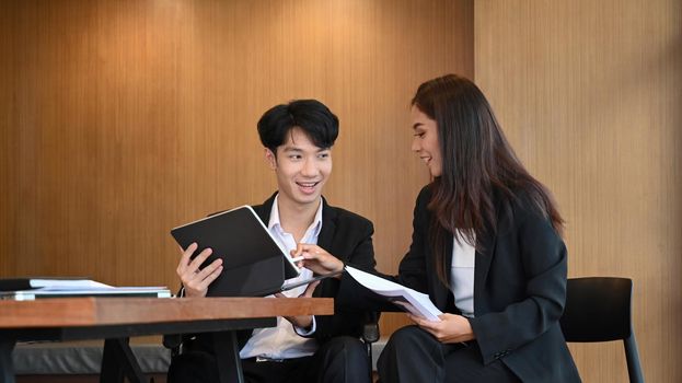 Two business people discussing project strategy together at office.