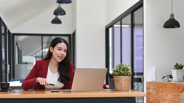 Young female entrepreneur working with laptop computer in modern workplace.