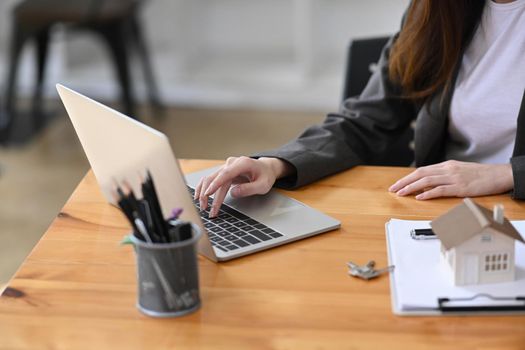 Real estate agent working with laptop computer in her office room. Mortgage and real estate investment.