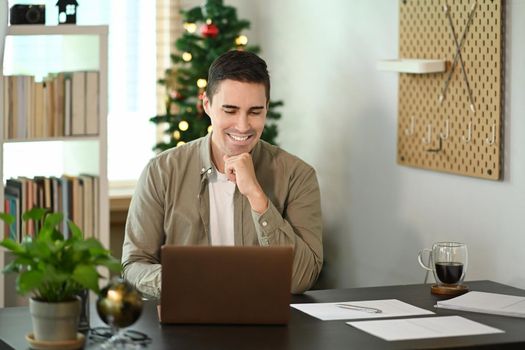 Smiling man having video conference with laptop computer.