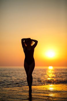 Silhouettes of a girl against the background of the sea and the setting sun. Selective focus