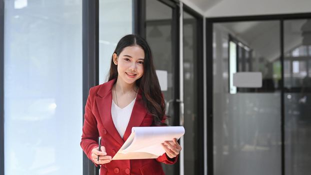 Attractive businesswoman holding reports and looking at camera.