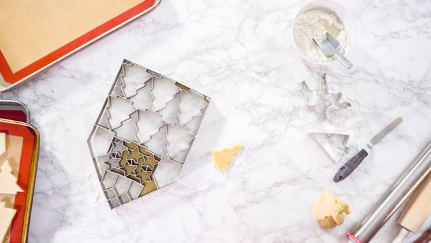 Flat lay. Cutting out sugar cookies with giant Christmas cookie cutter.