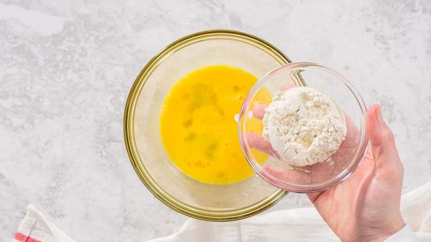 Flat lay. Step by step. Mixing ingredients in a glass mixing bowl to prepare chocolate mug cakes.