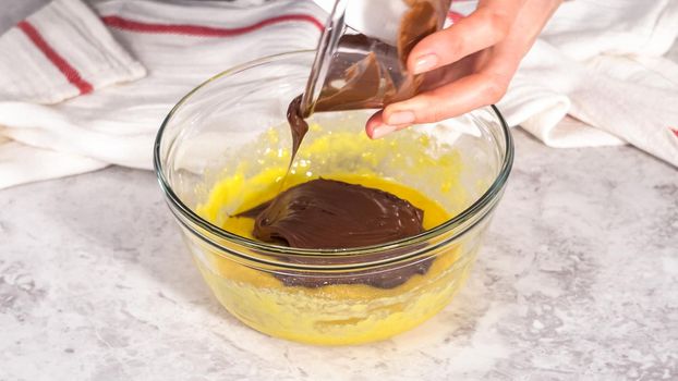 Step by step. Mixing ingredients in a glass mixing bowl to prepare chocolate mug cakes.
