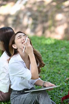 Cheerful asian woman sitting with her friend in the park.