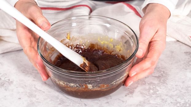 Step by step. Mixing ingredients in a glass mixing bowl to prepare chocolate mug cakes.