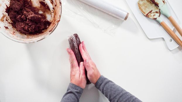 Step by step. Flat lay. Wrapping cookie dough into the plastic wrap to bake chocolate cookies.