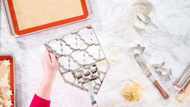 Flat lay. Cutting out sugar cookies with giant Christmas cookie cutter.