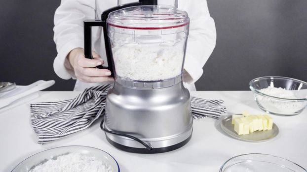 Mixing ingredients in a food processor to prepare homemade coconut cookies.