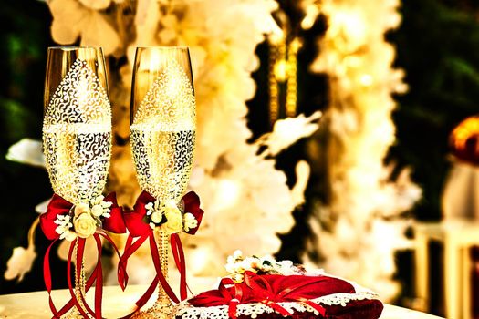 a marriage ceremony, especially considered as including the associated celebrations. Gold wedding crystal glasses of champagne with red ribbons and wedding decor