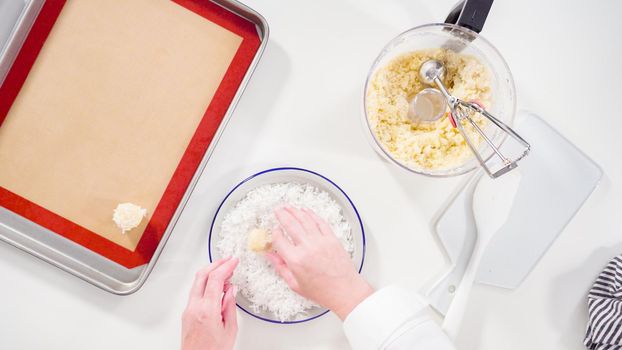Flat lay. Scooping cookie dough into the baking sheet to bake coconut cookies.