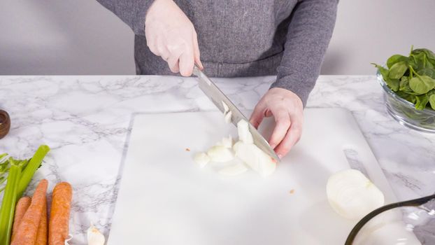 Curring vegetables on a white cutting board to cook vegetarian white bean soup.