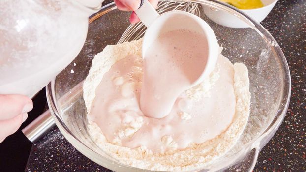 Mixing ingredients in a glass mixing bowl to make homemade pancakes.