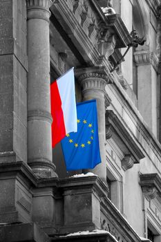 The flags of Poland and the European Union hang on the building