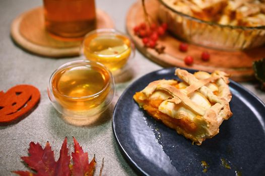 A piece of homemade pumpkin pie with a puff crispy crust on a plate, cups of hot tea, dry autumn maple leaves and red viburnum berries on a linen tablecloth. Time for tea. Breakfast. Autumnal themes