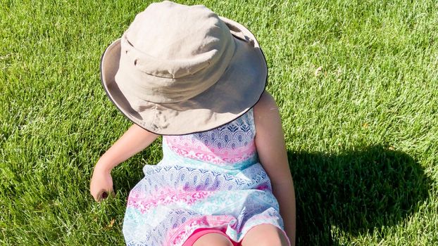 Little girl drawing with chalk on a sidewalk on the summer day.