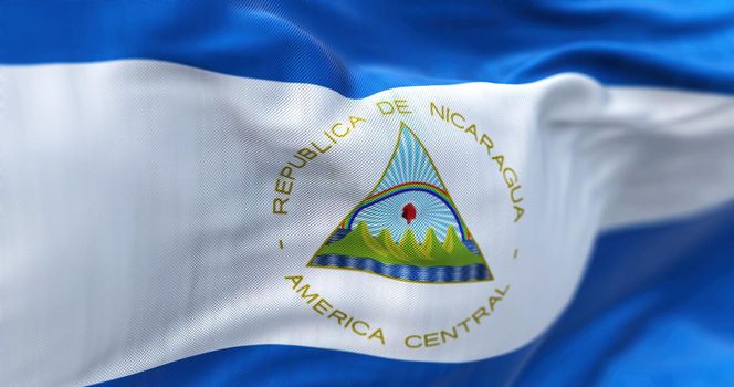 Close-up view of the Nicaragua national flag waving in the wind. The Republic of Nicaragua is a State of Central America. Fabric textured background. Selective focus