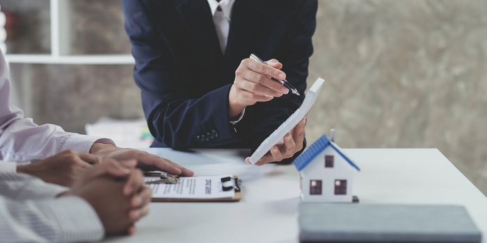 Business woman and young couple signing agreement for buying house. Bank manager and real estate concept..