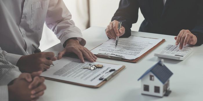 Real estate agent offer hand for customer sign agreement contract signature for buy or sell house. Happy asian couple signing a contract together at office. Real estate contact agreement concept.