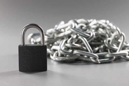 Closed padlock and metal chains on a gray background, close-up. Concept security, protective measures, closed borders