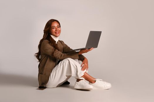 Studio photo Attractive young woman sitting with laptop over white background. People and technology concept.