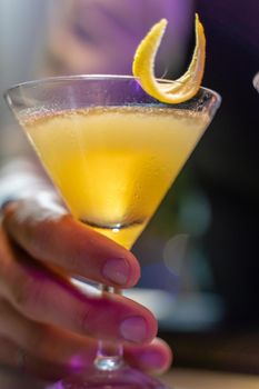 Close-up of a barman's hand serving a beautiful yellow cocktail on the bar counter in the nightclub. High quality photo