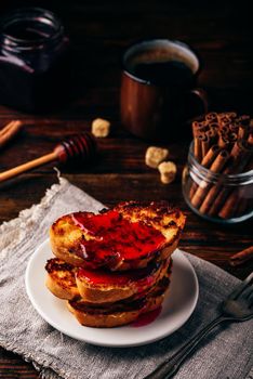 Stack of french toasts with berry syrup on white plate