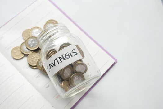 saving coins jar and calculator on table .