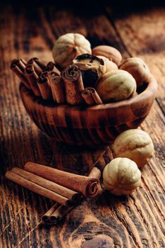 Cinnamon sticks and dried limes in wooden bowl on rustic table