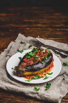 Baked eggplant stuffed with ground beef, tomatoes and spices on white plate. Traditional dish Karniyarik of turkish cuisine