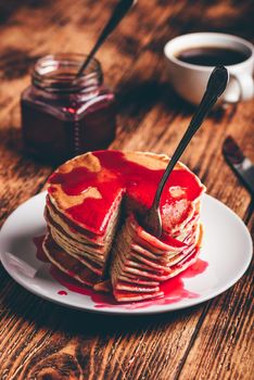 Stack of pancakes with berry fruit marmalade on plate over wooden surface