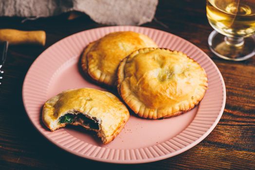 Oven Baked Pastries Filled with Blue Chives and Mushrooms on Plate with Glass of Wine. One Pie with Bite Taken Out of It