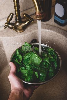 Hands of Chef Washing Fresh Spinach Leaves in Marble Sink