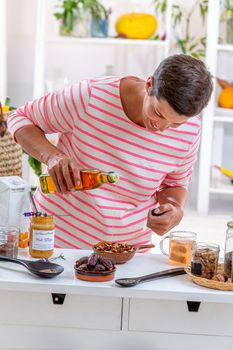 Woman pouring olive hule into a saucer containing dried fruit and fresh cereals