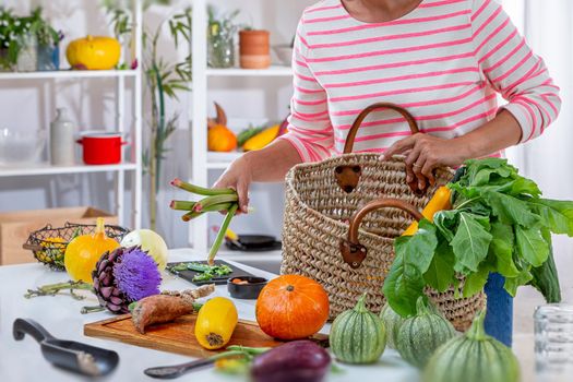 Young woman depositing vegetables on the work plan.