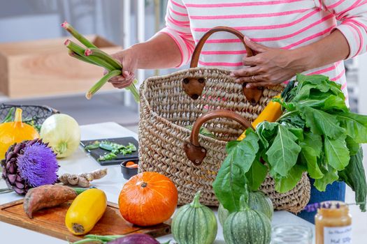 Young woman depositing vegetables on the work plan.