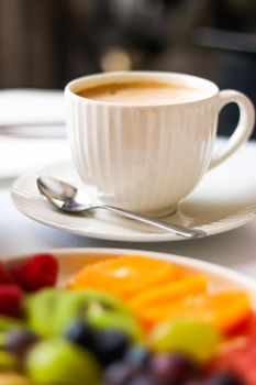 Breakfast and luxury, cup of coffee with milk and fruit platter on the served table for hospitality and gastronomy branding