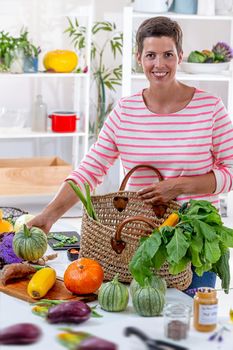 Young woman depositing vegetables on the worktop of the kitchen.