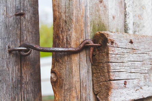 Old bolt. Vintage castle. Door on a hook. Old wooden fence. Closed territory.