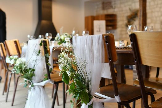 Wedding chairs decorated with white cloth and flowers