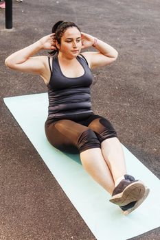 A charming brunette woman plus-size body positive practices sports in nature.